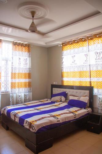 Schlafzimmer mit einem Bett mit blauer Bettwäsche und Fenstern in der Unterkunft Maakyere Apartments in Kintampo