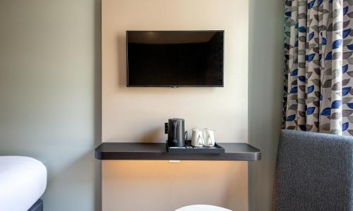 a room with a table with a tv on a wall at Royal National Hotel in London