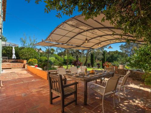un patio avec une table et des chaises sous un parasol dans l'établissement Holiday Home Le Clos du Pierredon by Interhome, à Grimaud
