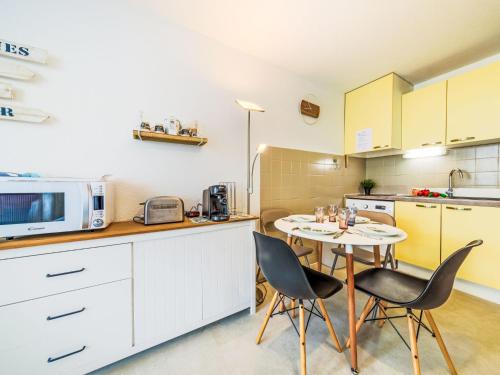 une cuisine avec une table et des chaises et un micro-ondes dans l'établissement Studio Les Floralies II-13 by Interhome, au Grau-du-Roi