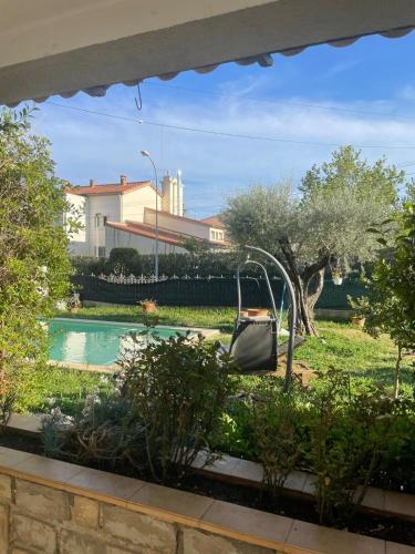 un jardin avec une balançoire et une piscine dans l'établissement T2 en rez de villa, à Sanary-sur-Mer