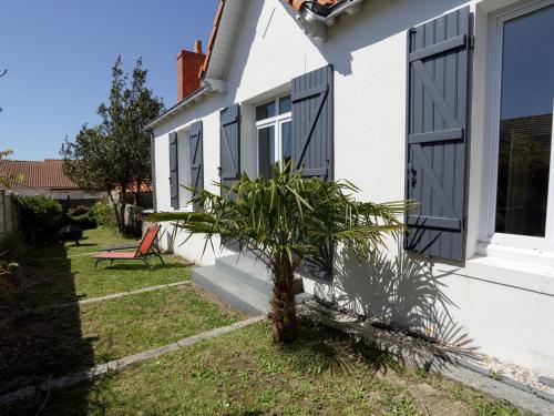 une maison avec des volets noirs et un palmier dans la cour dans l'établissement Holiday Home La Goélette by Interhome, à Pornic
