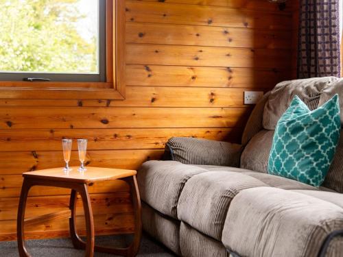 a living room with a couch and a table with wine glasses at Chalet Sycamore Hot Tub Lodge by Interhome in Launceston