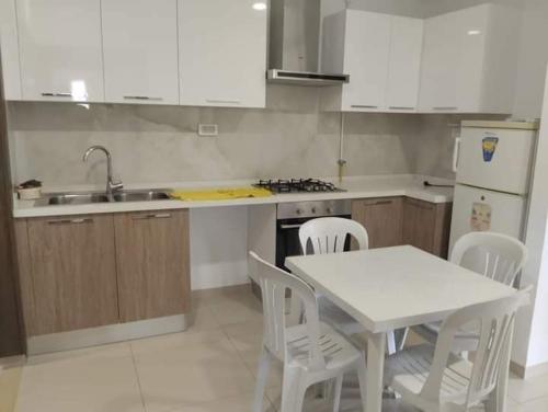 a kitchen with a white table and chairs and a sink at Résidence Sousse in El Ahmar