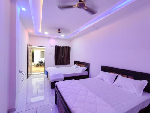 a bedroom with two beds and a ceiling fan at Family Homestay in Garudeshwar