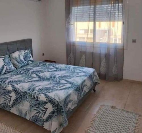 a bedroom with a bed with a blue and white blanket at Résidence Sousse in El Ahmar