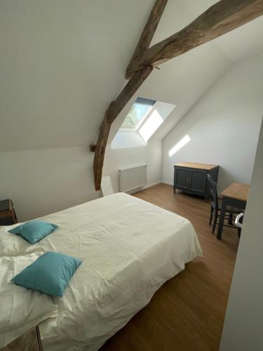 - une chambre avec un grand lit blanc et des oreillers bleus dans l'établissement La Marchanderie, à Spay