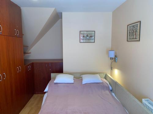 een kleine slaapkamer met een bed met 2 kussens bij Lakeside Apartman Hévíz in Hévíz