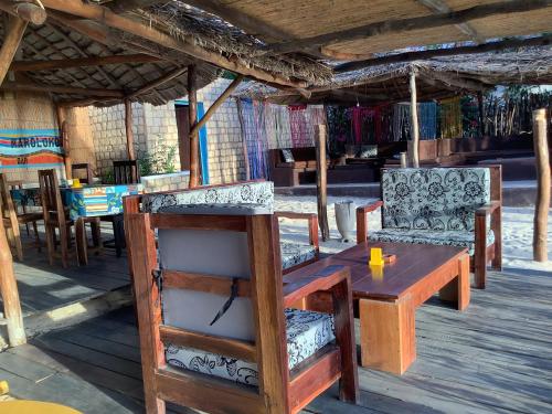 einen Holztisch und zwei Stühle sowie einen Holztisch und Stühle in der Unterkunft Hôtel Maroloko in Toliara