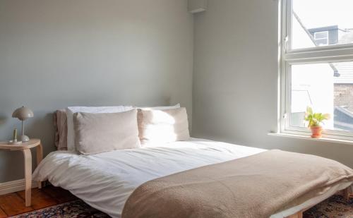 1 dormitorio con 1 cama con sábanas blancas y ventana en GuestReady - Victorian redbrick in heart of Dublin, en Dublín