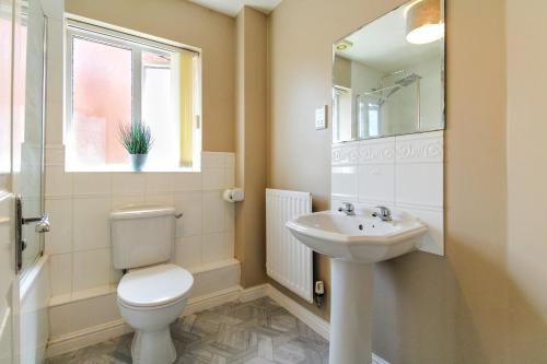 baño con aseo y lavabo y ventana en Spacious 4 Bedroom Home in Milton Keynes with Free Off Street Parking by HP Accommodation, en Milton Keynes