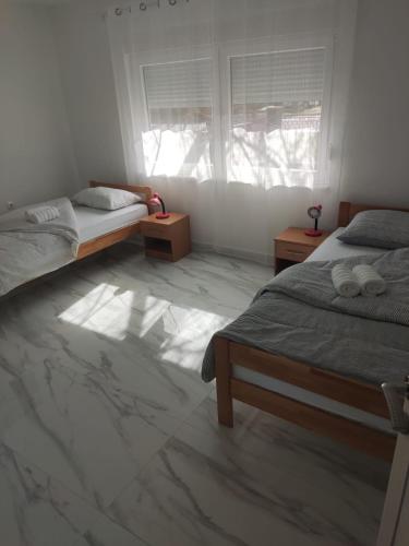 a bedroom with two beds and a window at Sobe Zimmer & Apartmani Nova Gradiška in Nova Gradiška