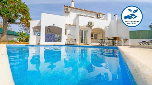 a villa with a swimming pool in front of a house at Villa Del Sol by Algarve Vacation in Quarteira