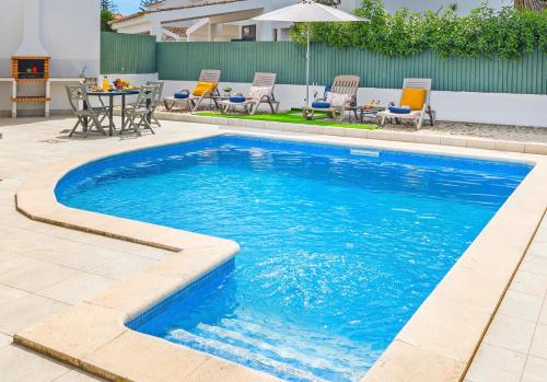 a swimming pool with a table and chairs in a yard at Villa Del Sol by Algarve Vacation in Quarteira