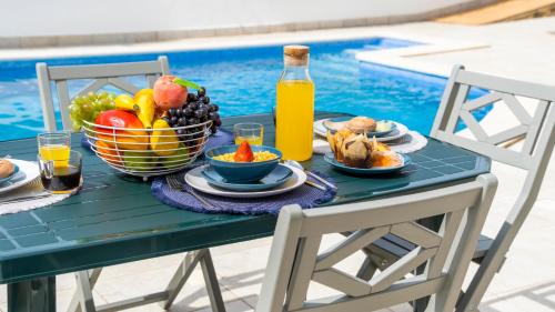 a table with fruit and juice next to a pool at Villa Del Sol by Algarve Vacation in Quarteira