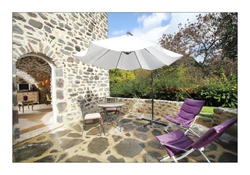 a table with two purple chairs and an umbrella at Ferme du Pic d'Allier in Saint Martin sur Lavezon