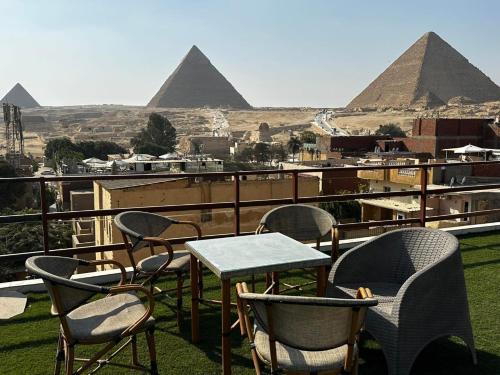 a table and chairs on a balcony with the pyramids at Narmer Pyramids View in Cairo