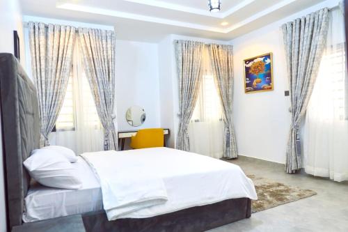 a bedroom with a bed and two windows at Lush Meadows Apartments in Kadobunkuro