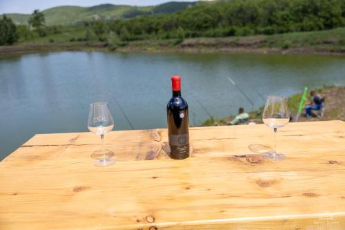 a bottle of wine sitting on a wooden table with two glasses at Mountain Lake JBS in Focşani