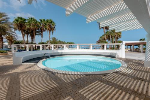 una piscina en un patio con palmeras en VOI Praia de Chaves Resort en Sal Rei