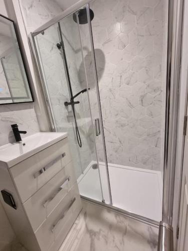 a white bathroom with a shower and a sink at Mill View Cottage at Pheasant Lane in Ráistín