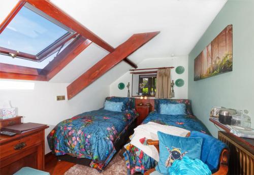 een slaapkamer op zolder met 2 bedden en een raam bij Tregondale Manor Farm in Liskeard