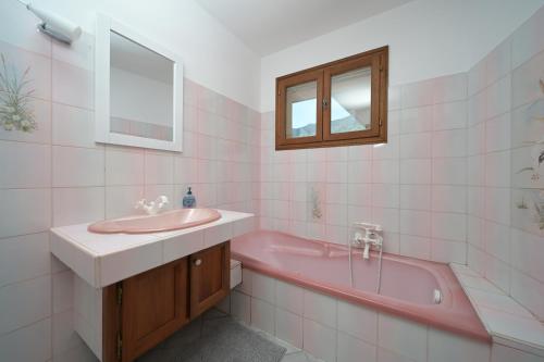 y baño con bañera rosa y lavamanos. en Gite 6 Personnes Boutx, en Boutx