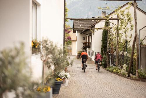 two people riding bikes down a narrow street at Weingarten Terlan - Rooms & Breakfast in Terlano
