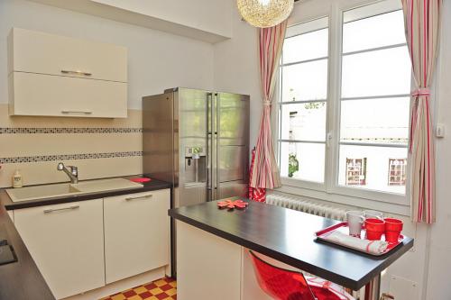 a kitchen with white cabinets and a black counter top at Appartement Les Hortensias in Avignon