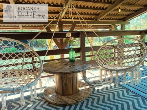 a table and chairs on a porch with a table and a glass bottle at Domek w Puszczy ,,Kocanka" in Mężyk