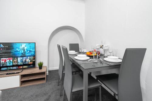 a dining room with a table with chairs and a television at Deluxe Four Bedroom House - Garden - Parking - Sleeps 7 - Netflix - 559T in Birmingham