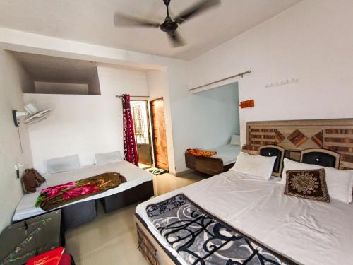 a bedroom with two beds and a ceiling fan at Jay Kuber Home stays in Garudeshwar