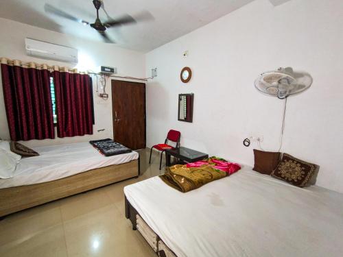 a room with two beds and a chair in it at Jay Kuber Home stays in Garudeshwar
