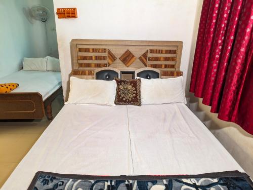 a bed in a room with two beds and red curtains at Jay Kuber Home stays in Garudeshwar