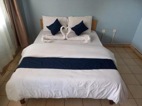 Una cama con dos toallas en forma de cisne. en Hotel Illusions, en Kakamega