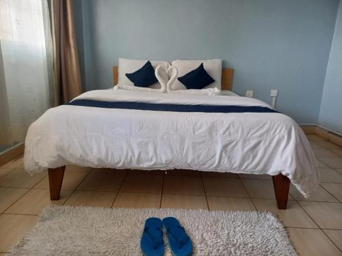 1 cama con 2 zapatillas azules en el suelo en Hotel Illusions, en Kakamega