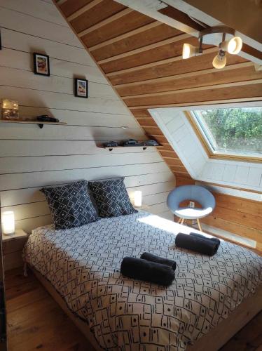 ein Schlafzimmer mit einem Bett im Dachgeschoss mit einem Fenster in der Unterkunft Le Calibrochet - 24 Heures du Mans in Saint-Ouen-en-Belin