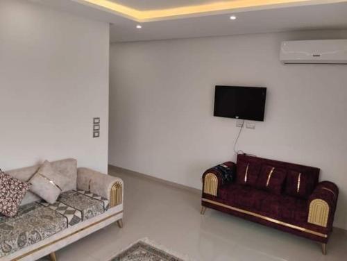 een woonkamer met een bank en een flatscreen-tv bij إقامة طلال in El Ahmar