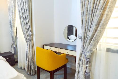 a yellow chair sitting next to a desk with a mirror at Lush Meadows Apartments in Kadobunkuro