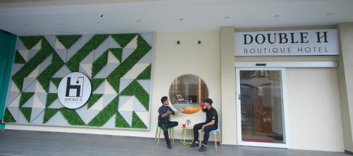 two men sitting at a table outside of a building at Double H Boutique Hotel in Kuala Terengganu