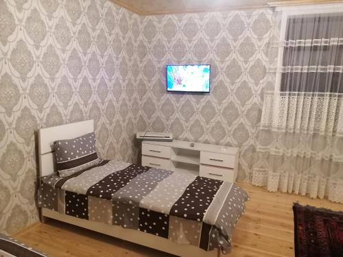 a bedroom with a bed and a tv on a wall at Eldeniz Nuxa House in Sheki