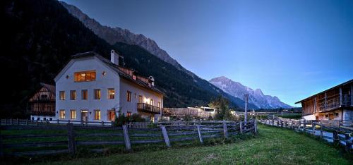 a building in a field with mountains in the background at Halbwöhrerhof in Anterselva di Mezzo