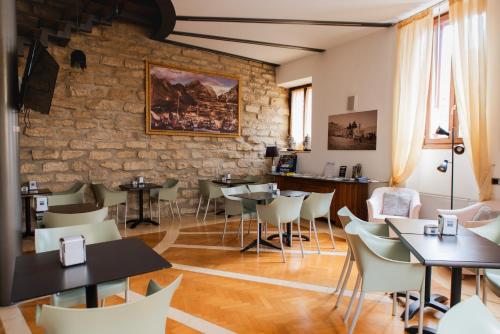 restauracja ze stołami i krzesłami oraz kamienną ścianą w obiekcie Arciduca Charming House Room & Breakfast w Arco