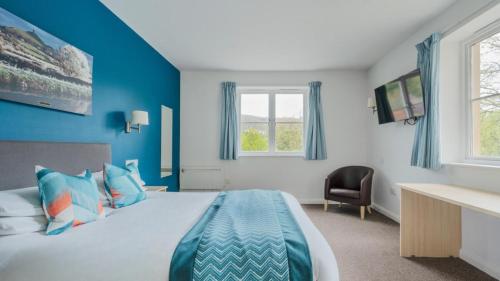een blauwe slaapkamer met een bed en een raam bij Wookey Hole Hotel in Wells