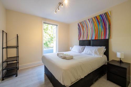 um quarto com uma cama grande e uma pintura colorida na parede em 4 bedroom Stunning Flat Near Westfield & Trains em Londres