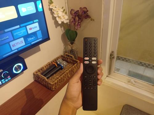 a person holding a remote control in front of a tv at Villa Gamping Favika Batu in Batu