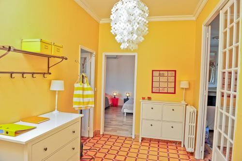 a yellow room with a desk and a chandelier at Appartement Les Hortensias in Avignon
