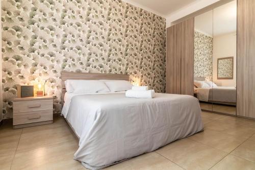 a bedroom with a large white bed with a wall at [20 minuti dal Duomo] Milano Smart Apartment in Sesto San Giovanni