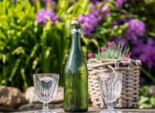 une bouteille verte et deux verres sur une table dans l'établissement les gîtes de Blandines II, à Peumérit