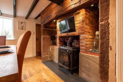 a brick fireplace with a tv on top of it at Pass the Keys Charming Cottage Stunning Views in Cheswardine